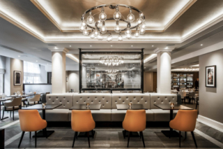 restuarant setting with a leather bench seat and four leather sinle seats warm setting and a big modern chandelier hanging from the ceiling.David Chatfield | Interior Photography in London
