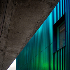 Corrugated exterior of a building with a changing colour, there is a rectangula window in the side. in london uk