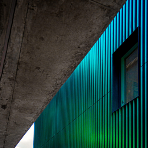 Corrugated exterior of a building with a changing colour, there is a rectangula window in the side. in london uk