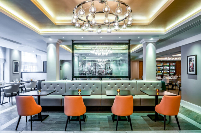 Dining suite Intyerior of a resturant with orange chairs grey furniture and a big designer light fitting on the ceiling.
