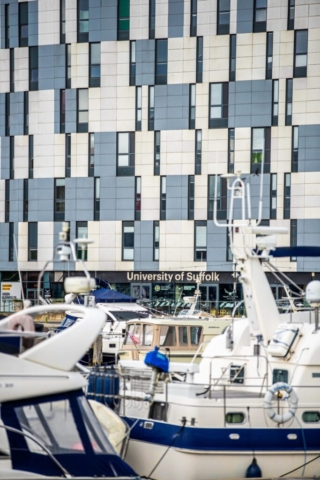Yachts mored up in the wet dock at the town of suffolk in front of the University of suffolk building