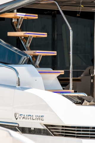 stern of a Super yacht with wooden steps in view with blue strip lights wraped around.