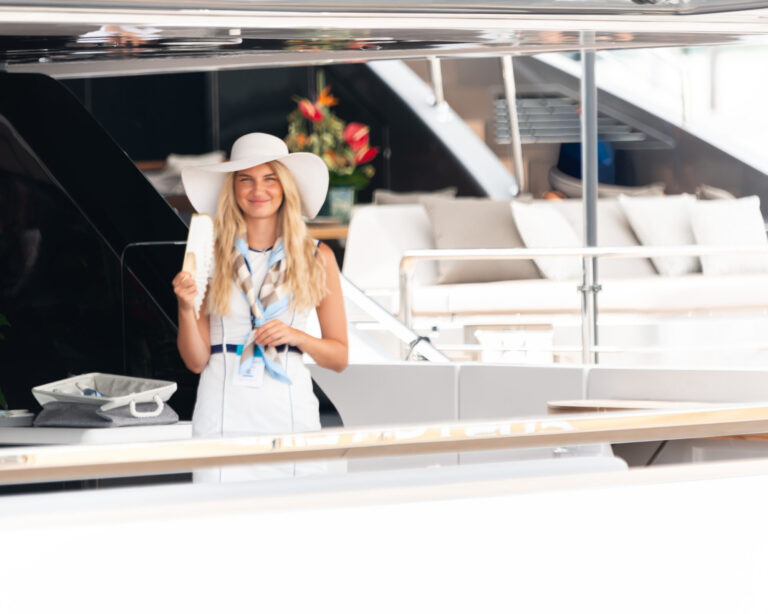 Female fanning herself on the stern of a superyacht in a hat