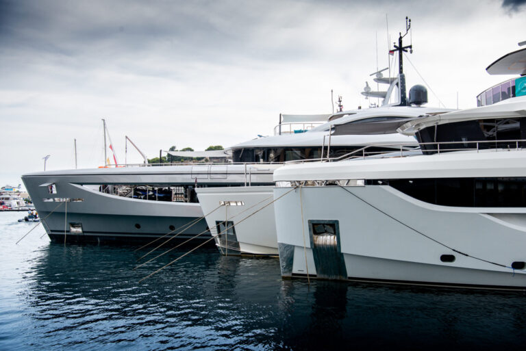 3 super yachts in port side by side with a dark cloudy sky.